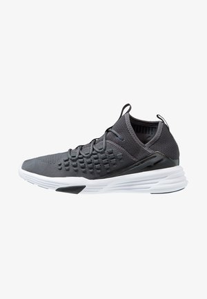 Chaussure de sport tricotée noire et gris foncé avec semelle blanche, partie supérieure texturée, languettes sur la languette et le talon, et design bas.