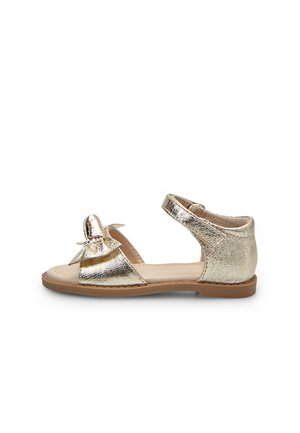 Sandalo metallizzato dorato con un fiocco sulla punta, due cinturini regolabili e suola piatta in gomma. Superficie strutturata con finitura liscia.