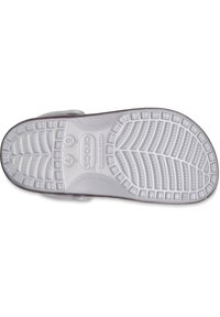 Weiße Gummisohle eines Crocs-Schuhs mit einem strukturierten, rutschfesten Muster und erhöhten Griffen sowie Markenzeichen. Flaches Design mit matter Oberfläche.