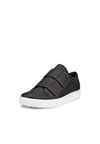 Baskets noires avec un dessus en cuir texturé, deux bandes Velcro en tissu et une semelle en caoutchouc blanche, présentant une pointe arrondie et des détails cousus.