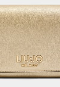 Portefeuille en cuir texturé doré avec logo embossé "LIU·JO MILANO". Présente une surface lisse et des coutures impeccables le long des bords.