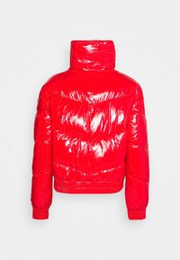 Czerwona pikowana kurtka puchowa z błyszczącym wykończeniem, wysokim kołnierzem i prążkowanym dołem. Posiada wzór pikowania w kształcie litery V oraz długie rękawy.