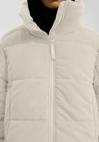 Beige Kord-Jacke mit Steppung, einem hohen Kragen und Frontreißverschluss. Verfügt über horizontale Steppabschnitte und eine Seitenasche.