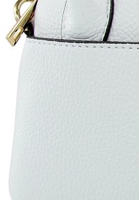 White textured leather bag with a gold zipper and hardware, featuring a curved top and contrasting black stitching near the zipper.
