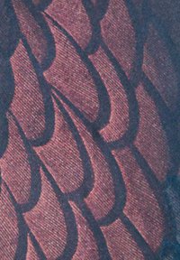 Sötét háttérrel rendelkező textil, amely rétegezett, pikkelyszerű mintákkal van díszítve bordó és rózsaszín árnyalatokban, textúrált megjelenéssel.