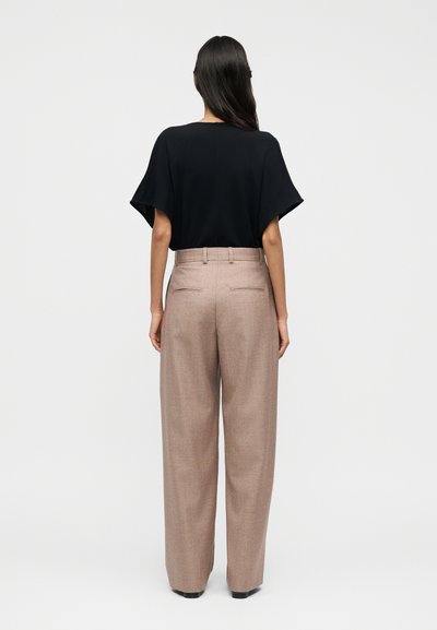 Μαύρο τοπ με κοντά μανίκια συνδυασμένο με μπεζ παντελόνια ψηλόμεσα και φαρδιά. Τα παντελόνια έχουν δύο πίσω τσέπες και διακριτική υφή.