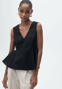 Black peplum top with a V-neck design, made of textured fabric, featuring tailored seams and a flared hem. Paired with light-colored trousers.