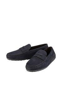Mocasines de ante azul marino con costuras en contraste, suela de goma flexible y una correa decorativa en la parte superior para un detalle adicional.