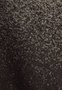 Tejido gris oscuro texturizado con un sutil patrón de manchas más claras, creando una apariencia suave y matizada. El material parece denso y esponjoso.