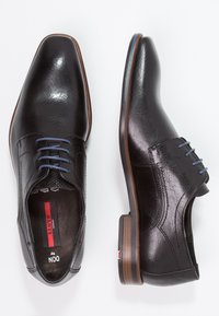 Black leather dress shoes with a smooth finish, pointed toe, blue laces, and a brown heel. Features perforated accents near the tongue.