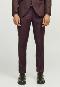 Pantalons de costume ajustés de couleur violet foncé avec un design épuré, une texture lisse, associés à des chaussures noires à lacets.