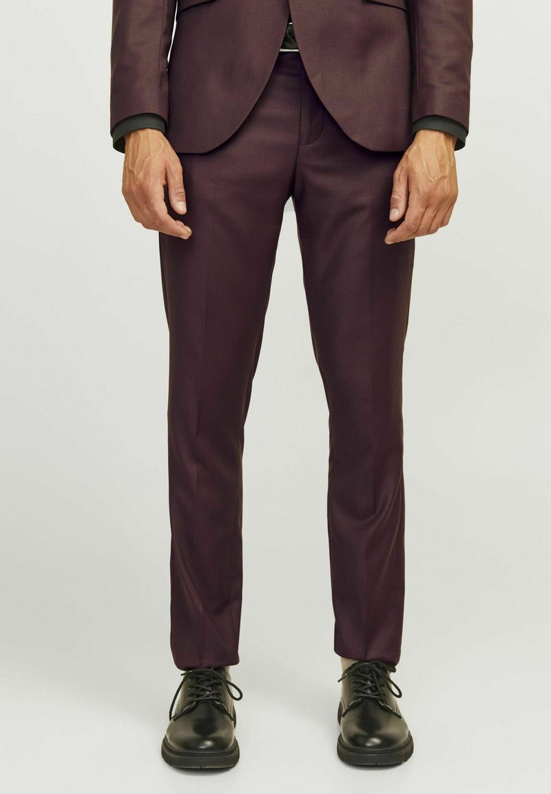 Pantalons de costume ajustés de couleur violet foncé avec un design épuré, une texture lisse, associés à des chaussures noires à lacets.