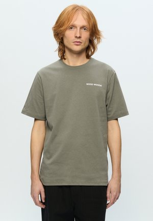 Olive green cotton t-shirt with short sleeves, round neckline, and white "WOOD WOOD" logo printed on the left chest. Regular fit.
