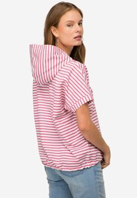 Sudadera de manga corta a rayas en rosa y blanco, con cordón, dobladillo elástico y un corte relajado, combinada con jeans de color azul claro.