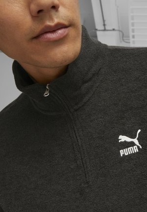 Grauem Reißverschluss-Fleece-Pullover mit hohem Kragen, strukturiertem Stoff und einem weißen Puma-Logo auf der linken Brust. Sichtbares silbernes Reißverschlussdetail.