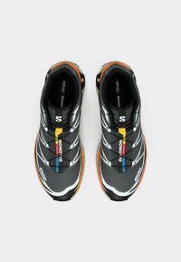 Μαύρα και γκρι αθλητικά παπούτσια με υφή στην επιφάνεια, με πολύχρωμες λεπτομέρειες, επενδεδυμένο πέλμα και σύστημα γρήγορου δέσιμου.