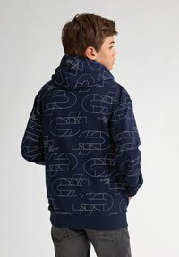 Sudadera con capucha de color navy que presenta un patrón geométrico blanco, textura suave y puños y bajo acanalados. Diseñada para la comodidad y el calor.
