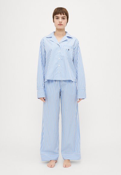 Blå og hvid stribet pyjamas sæt med en knap-op top og brede bukser. Har en brystlomme og manchetter på ærmerne. Blødt bomuldsstof.