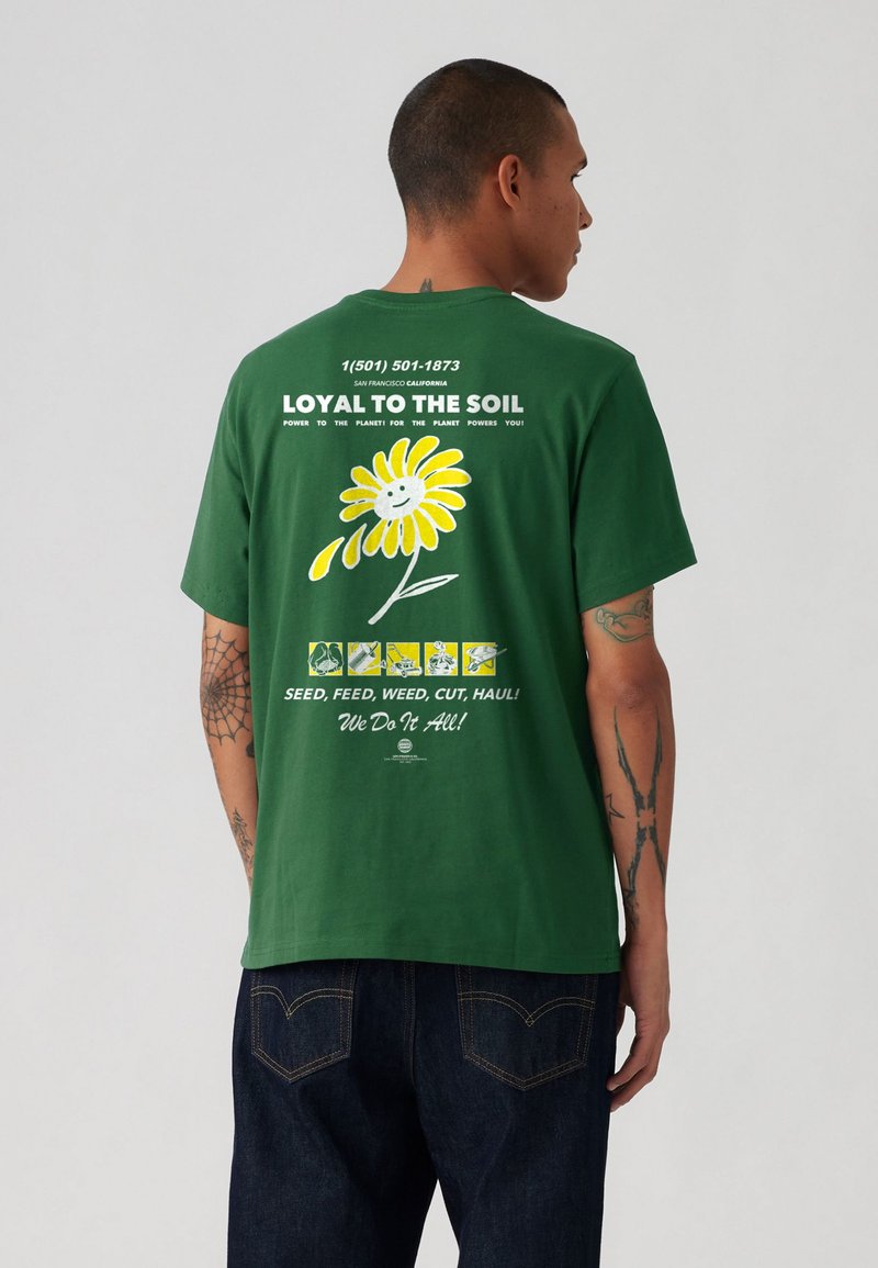 Tricou verde din bumbac cu un grafic de margaretă galbenă și text pe spate, mâneci scurte, croială lejeră, având detalii imprimate și guler rotund.