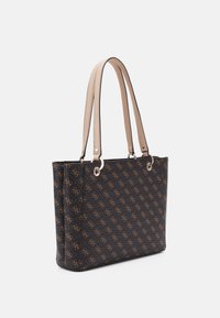 Sac fourre-tout noir avec motif de logo doré, doté de poignées beige clair et d'accents métalliques. Texture lisse, forme structurée avec un sommet ouvert.