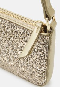 Petit sac à main doré avec une fermeture éclair, décoré de strass dorés et argentés rapprochés et une bandoulière en cuir assortie.