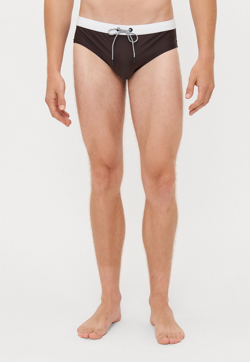 Schwarze Schwimmshorts mit einem kontrastierenden weißen Bund, ausgestattet mit einer Kordelzug-Verschluss. Der Stoff wirkt glatt und leicht.