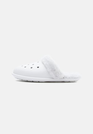 Fehér csúszó papucsok, puha, szürke műszőrme mandzsettával, perforált felsőrésszel a légáteresztés érdekében, és texturált talppal a tapadásért.