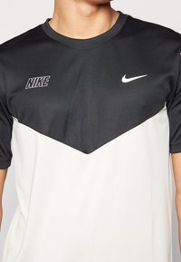 Svart och vit Nike sporttröja med korta ärmar, som har Nike-logotypen och swoosh på bröstet.