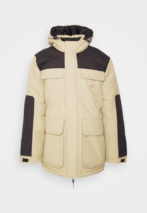 Béžová vypolstrovaná bunda s černými akcenty, vysokým límcem, několika předními kapsami a zipovým uzávěrem. Texturovaná tkanina pro teplo.