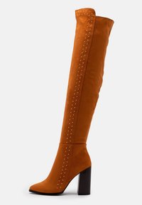 Stivale over-the-knee in suede arancione con tacco spesso nero, dotato di dettagli in metallo lungo il gambale e design con punta affusolata.