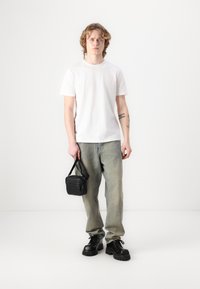 T-shirt bianco in cotone, jeans verde sbiadito, scarpe in pelle nera chunky e una piccola borsa a tracolla nera. Design semplice, look casual.