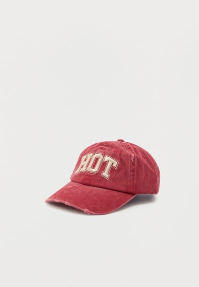 Red cotton baseball cap with a curved brim, embroidered "HOT" in cream, distressed detailing, and an adjustable strap at the back.