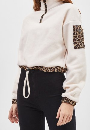 Fleece pullover in lichtroze met een half-ritskraag, voorzien van luipaardprint accenten op de zak en de zoom. Verstelbare koord in de taille.