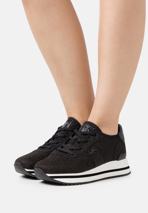 Czarne dzianinowe sneakersy z sznurowaniem. Posiadają gładki czarny skórzany akcent na pięcie oraz białą i czarną paskowaną podeszwę.