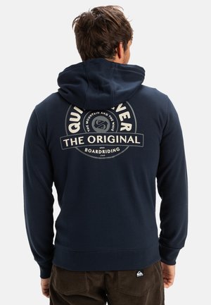 Navy blue hooded sweatshirt with a large circular logo on the back, featuring the text "Quiksilver THE ORIGINAL BOARDRIDING" in contrasting colors.
