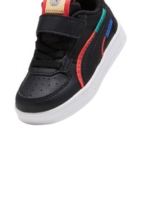 Zwarte lederen sneaker met rode, groene en blauwe accenten, voorzien van een klittenbandsluiting en een witte rubberen zool; geperforeerde neus voor ventilatie.