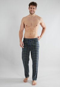 Pantalons à carreaux pour hommes en bleu marine et vert, avec une taille élastique et un cordon de serrage. Le tissu semble doux avec une texture lisse et une coupe ample.