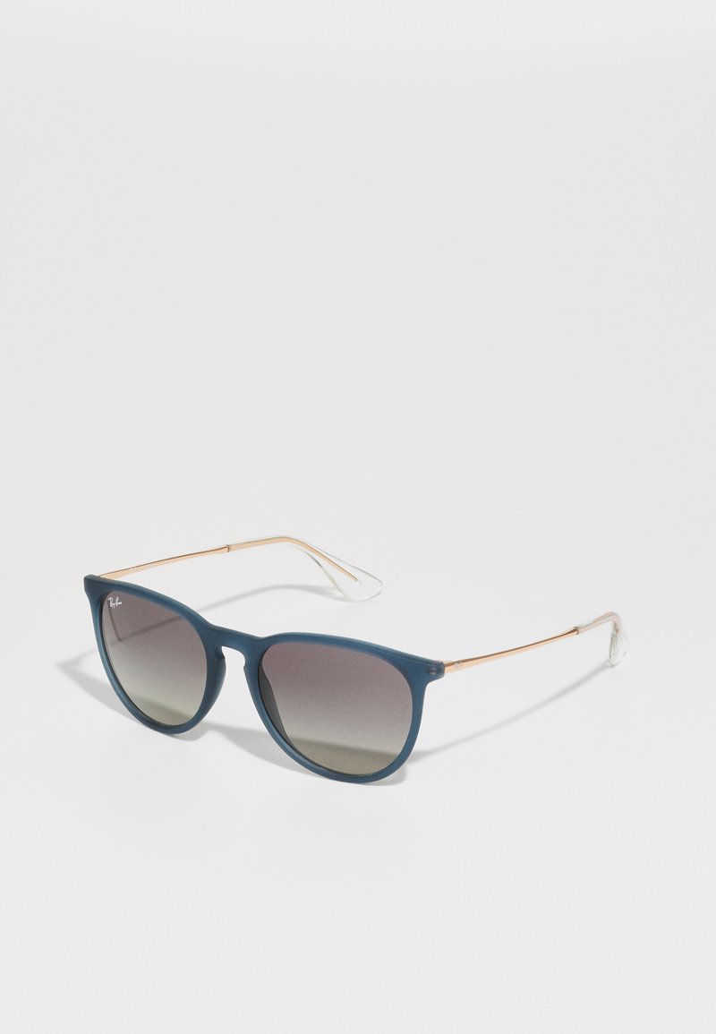 Óculos de sol azuis com lentes degradê, acabamento mate e hastes metálicas finas. Acentuados com pontas em plástico transparente para conforto.