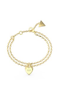 Bracelet double chaîne en or avec un charme en forme de cadenas en cœur portant l'inscription "GUESS EST. 1981" et une étiquette triangulaire.