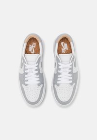 Para białych i szarych sneakersów Nike Air z białymi sznurówkami, perforowanym przodem i korkowymi wkładkami z logo Nike Air.