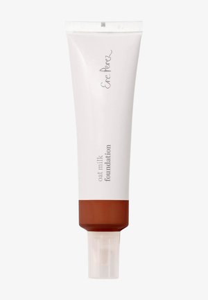 Fond de teint au lait d'avoine dans un tube beige clair avec une étiquette blanche. Doté d'un capuchon transparent et d'une base marron. Texte imprimé sur le côté.