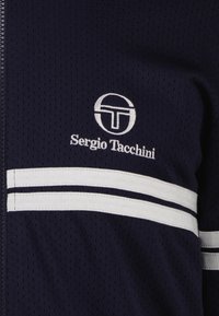 Marineblaue Jacke mit Reißverschluss aus perforiertem Material, ausgestattet mit weißen horizontalen Streifen und einem gestickten Logo mit der Aufschrift "Sergio Tacchini."