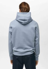 Light blue sweatshirt with a large hood, smooth texture, elastic cuffs, and waistband. Features a minimalist design with no visible logos.
