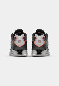 Black and gray athletic shoes with a textured upper and orange accents. Features a thick, transparent sole with cushioned heel support.