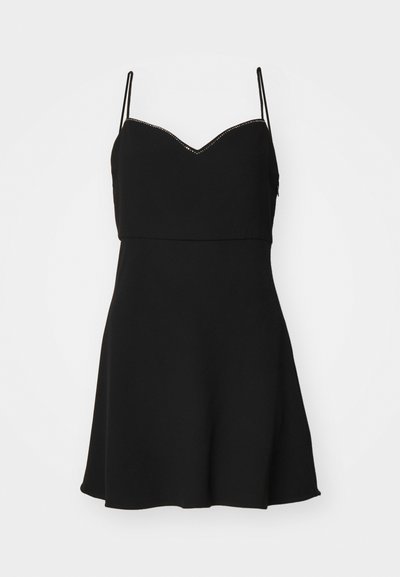 Robe noire avec un corsage ajusté, des bretelles spaghetti et une jupe évasée. Présente une encolure à bords festonnés avec des coutures décoratives.