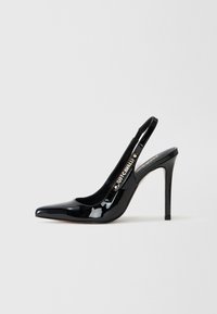 Pump slingback in vernice nera con punta affusolata, alto tacco a stiletto e un accento dorato sulla fascia con il nome del marchio.