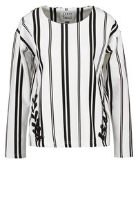 Långärmad skjorta med svartvita vertikala ränder, rund halsringning och dekorativ snörning på sidan.