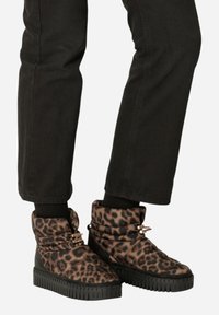 Botas acolchadas con estampado de leopardo y suela de goma negra, que presentan un diseño de puño doblado y acentos de hardware en tono dorado.