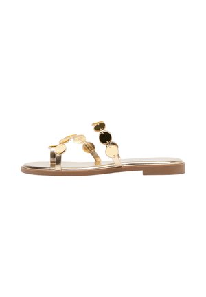 Flache goldene Sandale mit zwei dünnen Riemen, die mit glänzenden runden goldenen Scheiben verziert sind, und einer braunen Sohle.