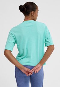 Mintgrøn kortærmet t-shirt med afslappet pasform, lavet af struktureret stof. Bagudsigt viser minimale sømme og ingen synlige logoer.